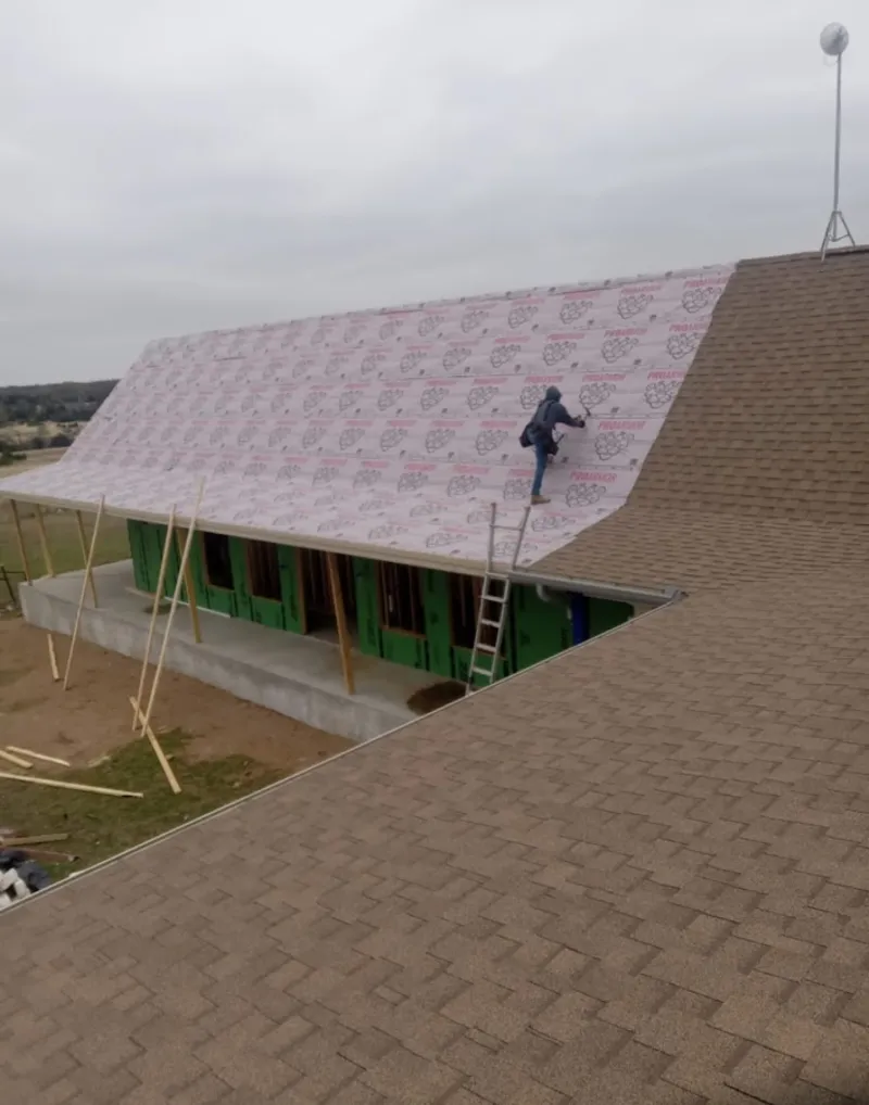 Worker preparing underlayment for a metal roof installation in Kewanee